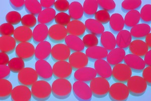 Medicine tablets illuminated with red light over blue background. 