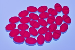 Medicine tablets illuminated with red light over blue background. Large depth of focus (tilted lens)