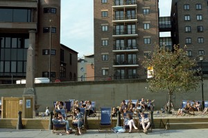 Newcastle-upon-Tyne, September 2011: missing the chance of going to any proper beach, inhabitants of Newcastle replace the sea with their river, and add some sand on the sidewalks of Quayside. The photo depicts several people sunbathing in a rare sunny day.