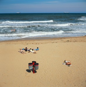 Tynemouth, England - June 26, 2011: this notoriously cold beach in Tyneside does not attract too many sunbathers. On this rare sunny day a few people attempt the outdoors and share the view with two commercial ships in the distance. Focus is on the foreground.