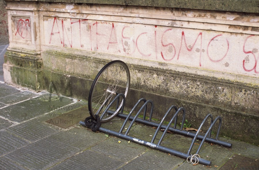 Graffiti on a wall pro "Antifascismo" (Antifascism). One bicycle was stolen - only the chained front wheel is visible Piazza Dante Spring 2013