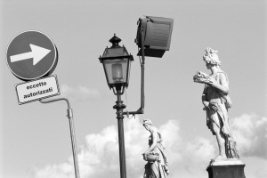Florence, Italy: the city is so full of artworks that it is impossible to separate it from the normal, modern urban decor necessary for the functioning of the town. Street sign and streetlamp with some statues situated along the River Arno. Scan from Acros 100