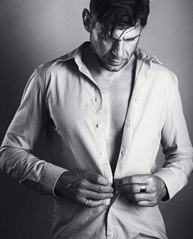 Handsome man unbuttons his shirt - studio shot
